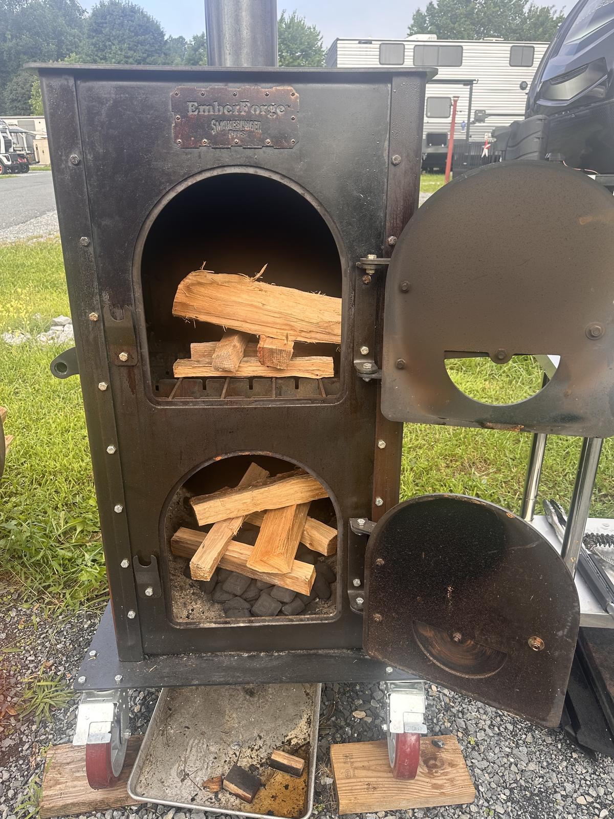 The EmberForge live-coal burner with its doors open and oak splits burning inside