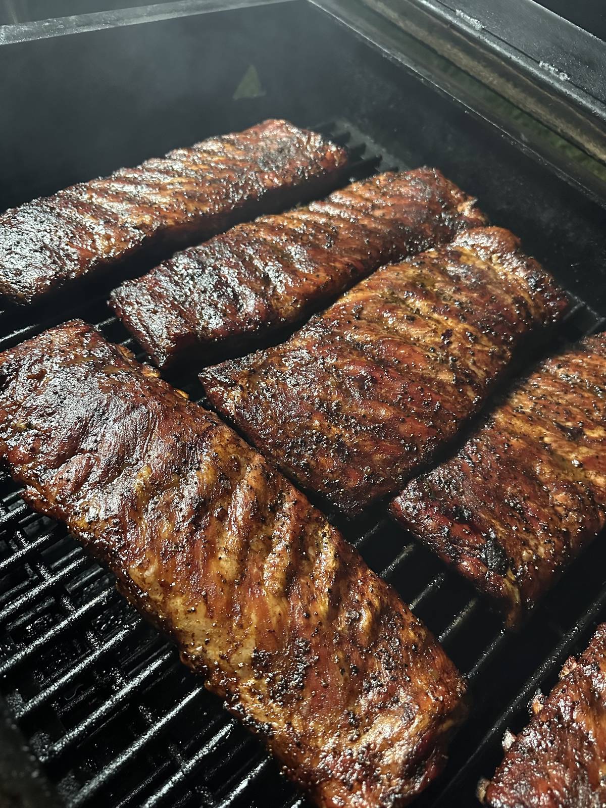 Rib racks with dark bark on a grill grate