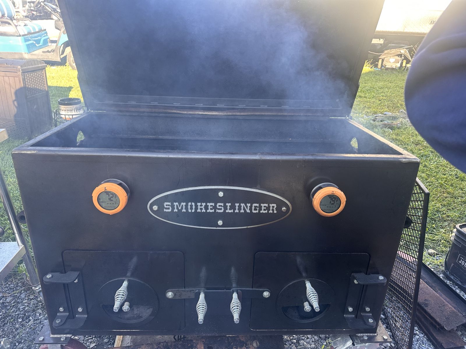 Front of a Smokeslinger smoker with two orange digital thermometers clipped on